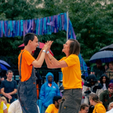 A performing duo on stage stood with their hands held together.