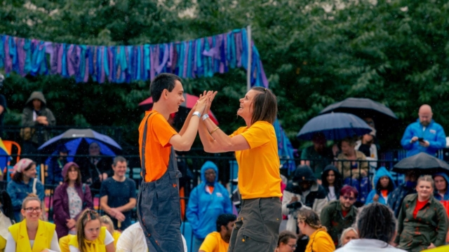 A performing duo on stage stood with their hands held together.