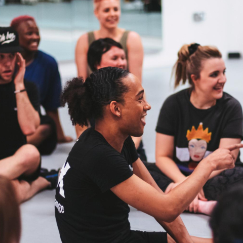 A group of people sat on the floor of a dance studio.