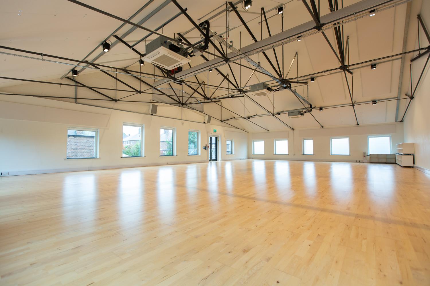 A brightly lit dance studio with large windows and laminate flooring.