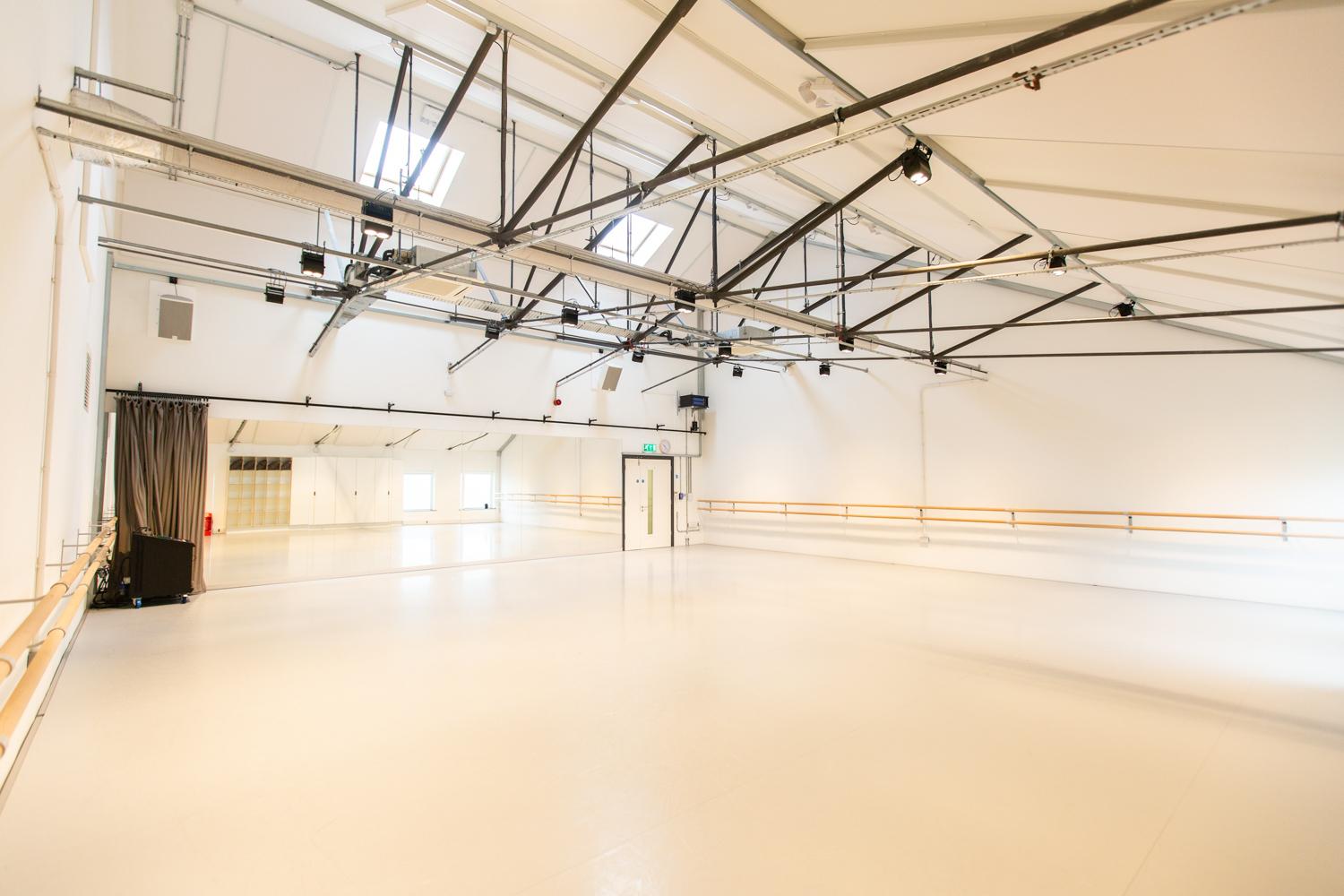 A brightly lit dance studio with mirrored walls.