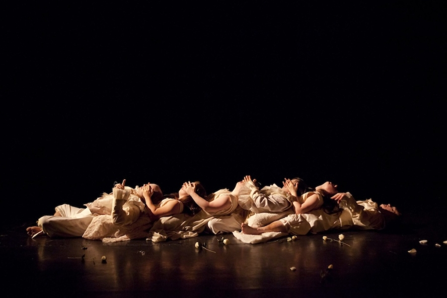 Group of dance performers lay down on the stage floor.