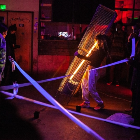 A group of people carrying long, glowing neon tubes.