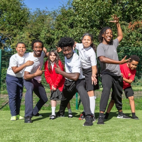 A group of primary school children playing outside on some grass.